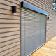 Moderne Holzfassade mit Jalousien und eleganten Wandleuchten für stilvolle Beleuchtung.