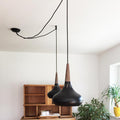 s.luce Modular Distanzabhänger mit zwei pendelnden schwarzen Leuchten und Holzdetails in modernem Raum.