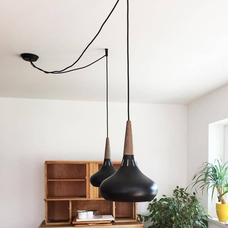 s.luce Modular Distanzabhänger mit zwei pendelnden schwarzen Leuchten und Holzdetails in modernem Raum.