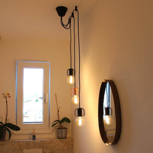 Suspensions distanciées modulaires de s.luce avec trois luminaires suspendus et un miroir moderne en arrière-plan.