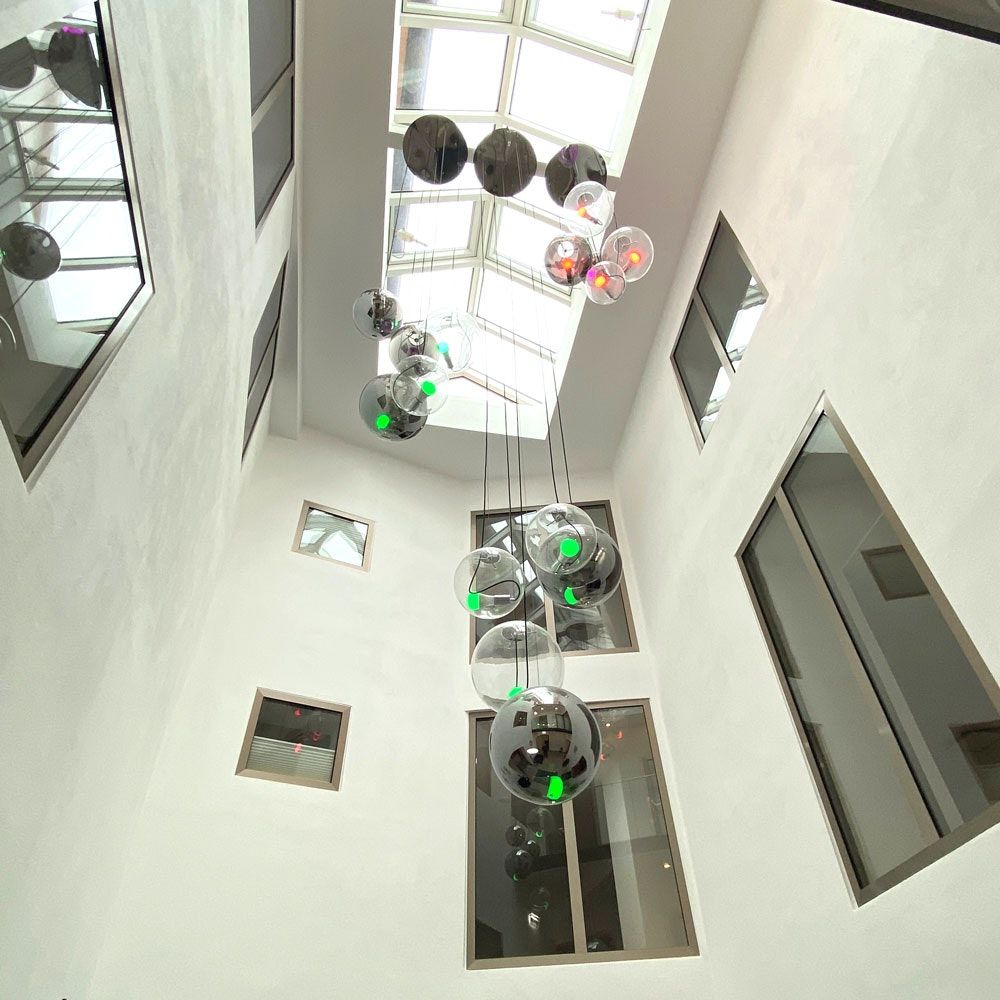 Moderne s.luce Sphere Galerieleuchte mit klaren und rauchfarbenen Glaskugeln in einem hellen Treppenhaus.