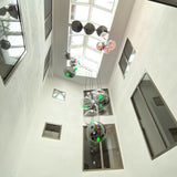 Moderne s.luce Sphere Galerieleuchte mit klaren und rauchfarbenen Glaskugeln in einem hellen Treppenhaus.