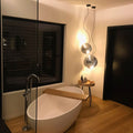 Moderne Badezimmeransicht mit s.luce Sphere Hängeleuchten über freistehender Badewanne und Holzfußboden.
