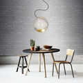 Moderne s.luce Sphere Pendelleuchte in rauchfarbener Glas-Hängelampe über einem minimalistischen Tisch.