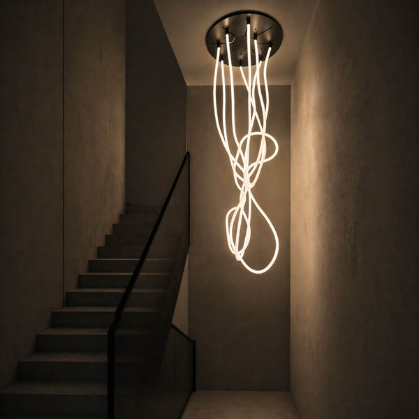 s.luce Arion organische Flex LED Hängelampe Licht-Schlauch Warmweiß im modernen Treppenhaus mit kreativen Lichtformen.