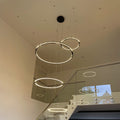 s.luce Atom Ring LED-Hängelampe in einem modernen Treppenhaus mit schwebenden Metallringen.