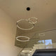 s.luce Atom Ring LED-Hängelampe in einem modernen Treppenhaus mit schwebenden Metallringen.