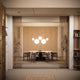 Moderne Esszimmeransicht mit hängenden Lampen, Holzregalen und eleganter Tischgruppe.