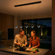 s.luce Beam LED Esstisch-Pendelleuchte Balken 120cm über einem modernen Küchentresen mit Paar beim Kochen.