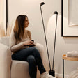 s.luce Beam LED Stehleuchte 2-flammig 145cm Touchdimmer neben einer Person in einem modernen Raum.