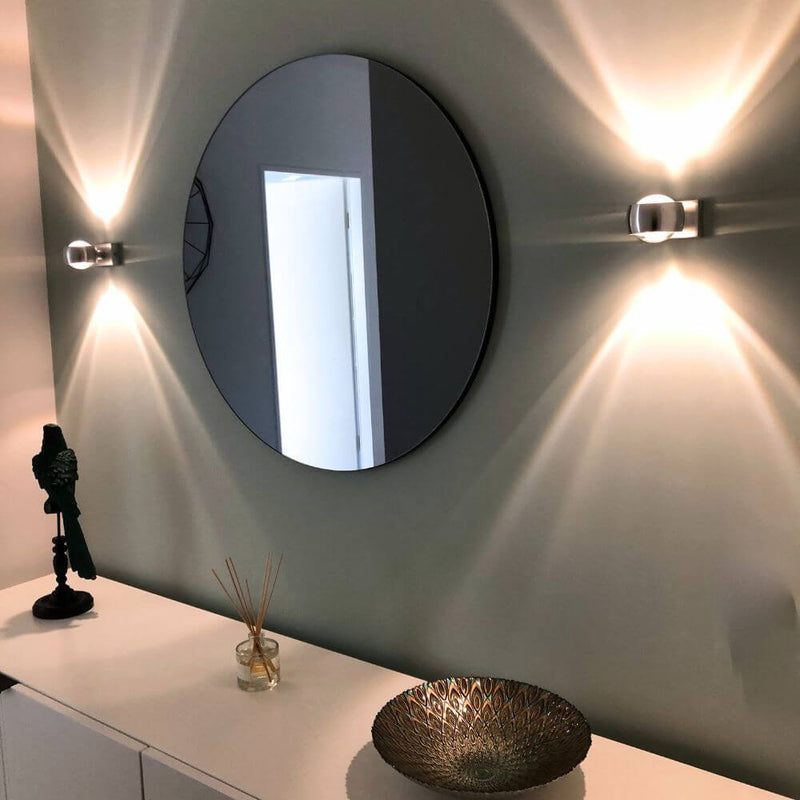 s.luce Beam Wandleuchte Up&Down mit Linsen an einer Wand, moderne Einrichtung mit runder Spiegel und Dekoration.