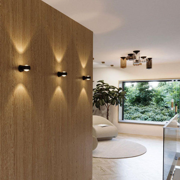 s.luce Beam Wandleuchte Up&Down mit Linsen in modernem Wohnraum mit Holzpaneelen.
