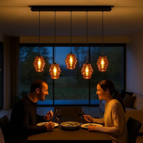s.luce Echos Esstischleuchte mit 5 mundgeblasenen Glaskörpern über einem Esstisch in stilvollem Ambiente.