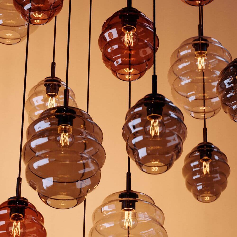 s.luce Echos Galerieleuchte mit 12 Pendelleuchten in verschiedenen Glasfarben, inspiriert von Wasserbewegungen.