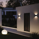 Moderne Ixa LED-Wandleuchten an einer Hauswand bei Nacht, strahlend und stilvoll in einem Garten.