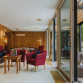 Elegante s.luce Ring Air LED Wand- und Deckenleuchte in modernem Wohnraum, rot gepolsterte Sessel und Holzverkleidung.