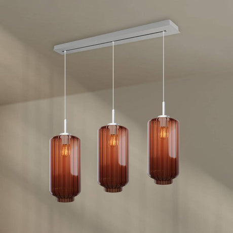 s.luce Velo Esstisch-Pendelleuchte 3-flammig 120cm Ø 18cm mit eleganten, braunen Glasleuchten über einem Esstisch.