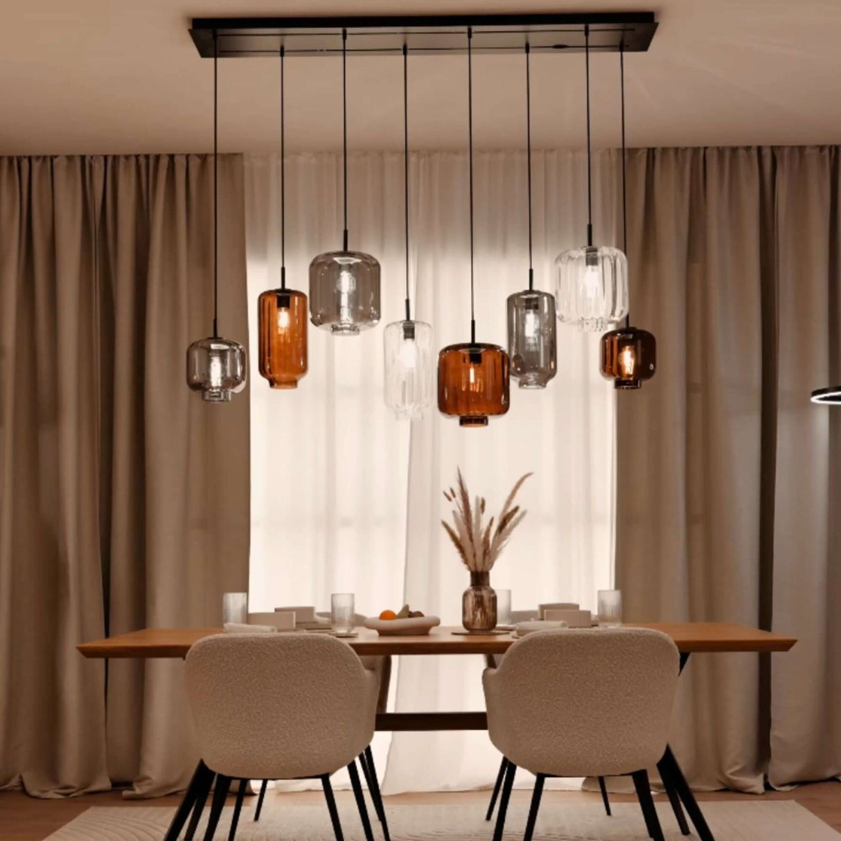 s.luce Velo Esstischleuchte 8-flammig 200cm 3-reihig Ø 18/20/25cm mit eleganten Glaskörpern über einem Esstisch.