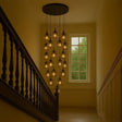 s.luce Velo 20-flammige Galerieleuchte über Treppe mit eleganten Pendelleuchten in warmem Licht.