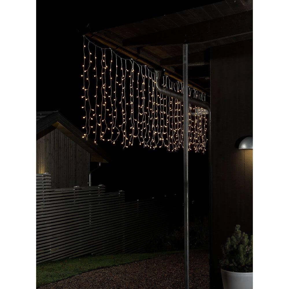 LED Lichtervorhang mit weißen Globes 200 Warmweiße Dioden IP44 hängen im Dunkeln und erhellen die Nacht.