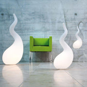 Lámpara de pie Alien M de 65 cm Liquid-Light blanca junto a un sillón verde en un interior moderno.