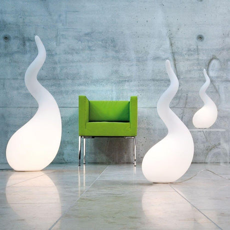 Alien M lampada da terra 65 cm Liquid-Light bianca accanto a una poltrona verde in un interno moderno.