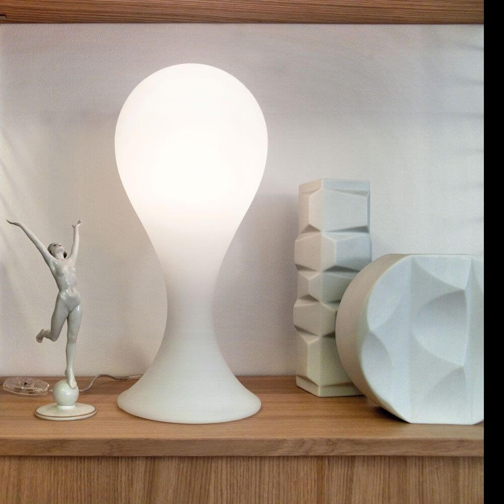 Drop-4S Tischleuchte 40cm Liquid-Light Weiß auf einem Regal, kombiniert mit modernen Dekorationselementen.