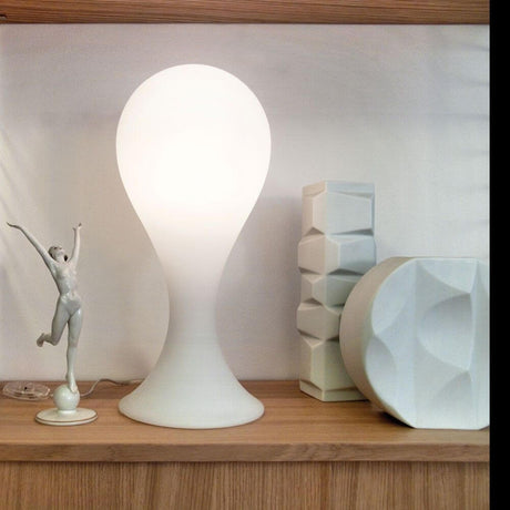 Drop-4S bordlampe 40 cm Liquid-Light Hvit på en hylle, kombinert med moderne dekorasjonselementer.