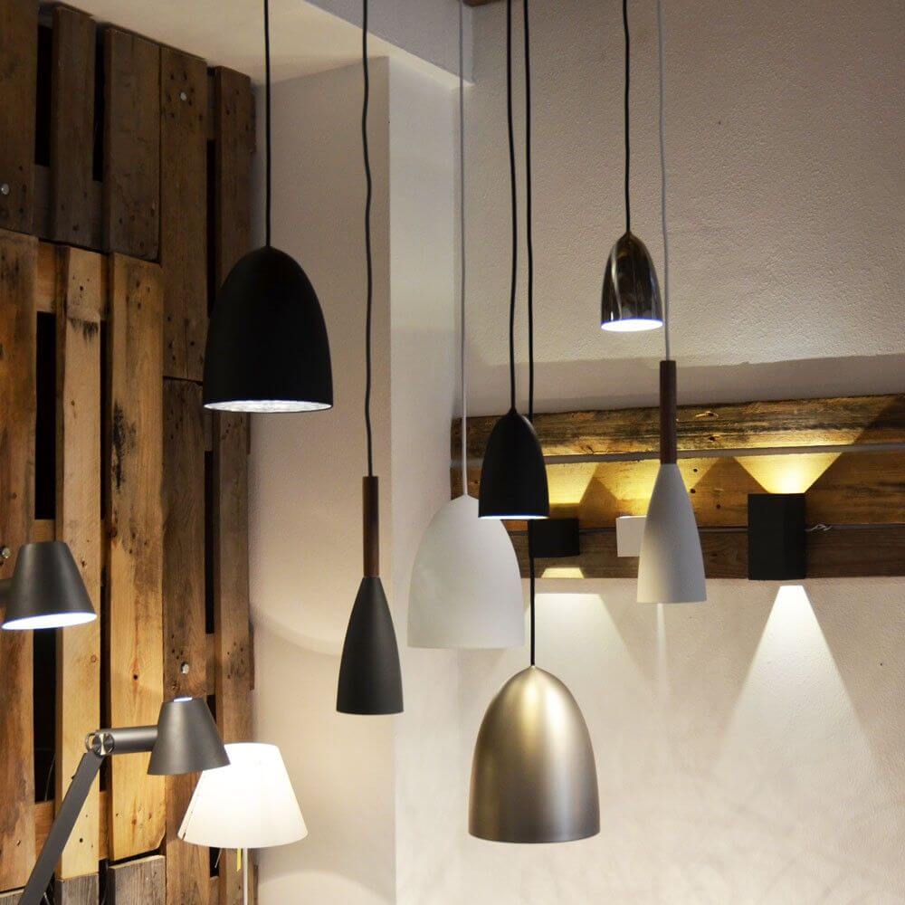 Pendelleuchte Pure Schwarz, Walnuss in einem modernen Raum mit Holz-Elementen und verschiedenen Lichtquellen.