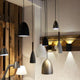 Pendelleuchte Pure Schwarz, Walnuss in einem modernen Raum mit Holz-Elementen und verschiedenen Lichtquellen.