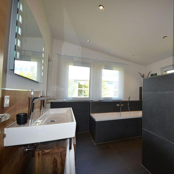 Modernes Badezimmer mit eleganter Badewanne, stilvollem Waschbecken und Tageslicht durch große Fenster.