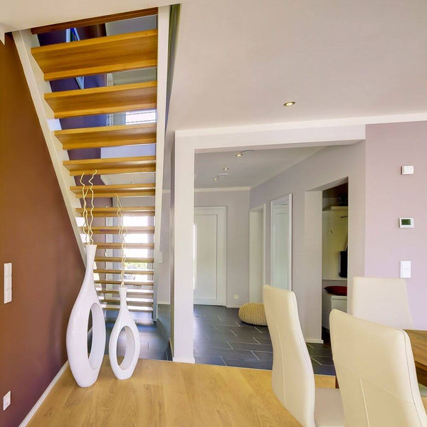 Moderne Treppe mit Holzstufen und eleganter Inneneinrichtung in einem lichtdurchfluteten Raum.